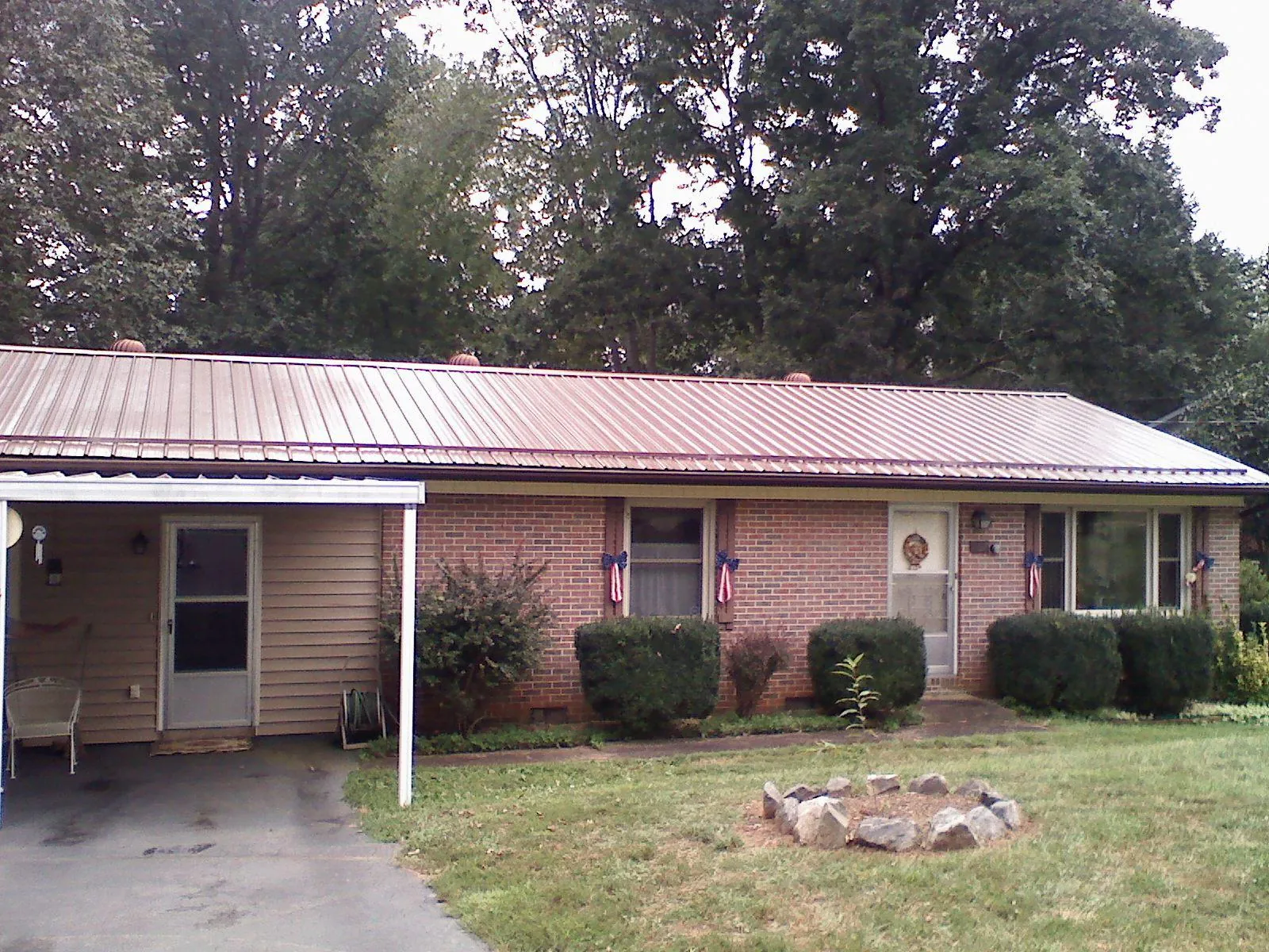 Bronze metal roof and carport on a brick ranch home — Roof Repair work by our crew in Greene
